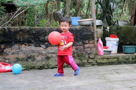 HAI DUONG, VIETNAM, September, 10: Asian boy about 1 year old, play football alone in the yard on September, 10, 2013 in Hai Duong, Vietnam.のeditorial素材