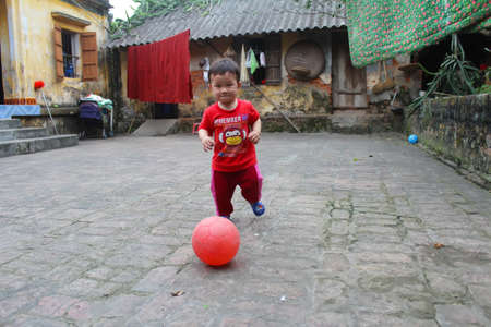 HAI DUONG, VIETNAM, September, 10: Asian boy about 1 year old, play football alone in the yard on September, 10, 2013 in Hai Duong, Vietnam.のeditorial素材
