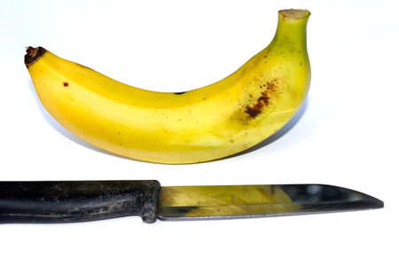 Ripe banana and knife isolated on white backgroundの写真素材