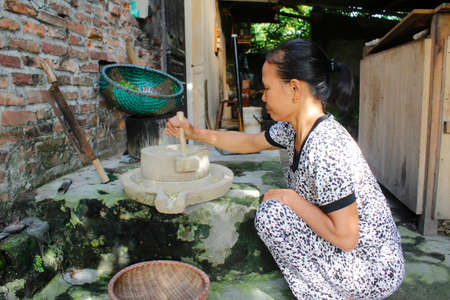 HAI DUONG, VIETNAM, AUGUST, 12: woman grinding green bean with millstone on August, 12, 2014 in Hai Duong, Vietnam.のeditorial素材
