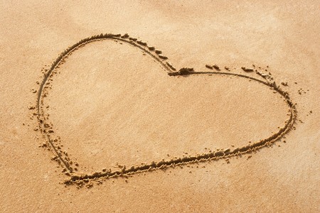 Heart shape symbol drawn on sandy beachの写真素材
