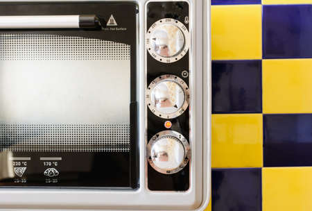 Electric Oven gray-black color on a background of blue-yellow tileの写真素材