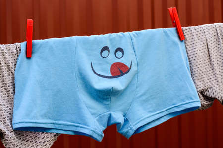 Pants with painted smiley, drying after washing on the streetの写真素材