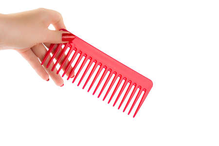 Female hand holding a red comb on a white backgroundの写真素材
