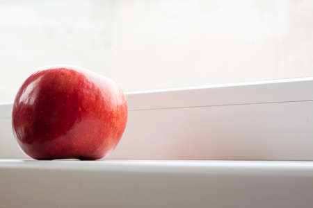 Red apple on a window sill. Daylight.の写真素材