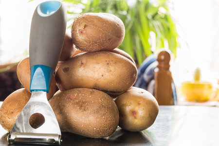 A lot of raw potatoes lying on the table near the window. Still life of potatoes.の写真素材