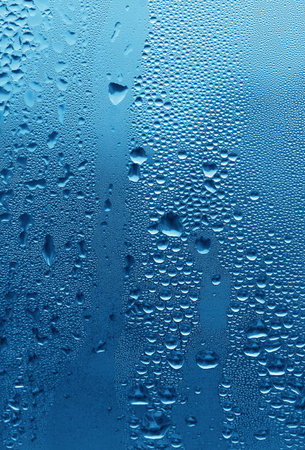 Natural large and fine water drops on blue glass backgroundの写真素材