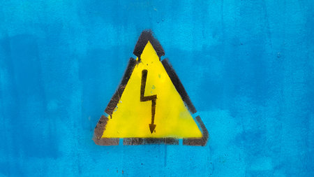 Bright yellow warning sign High voltage on blue backgroundの写真素材