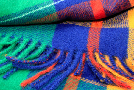 Texture of a bright multicolor scarf with fringe, closeup background