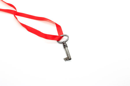 Vintage silver key on red ribbon isolated on white backgroundの写真素材