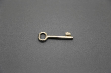 Old metal key on gray paper background, close-up