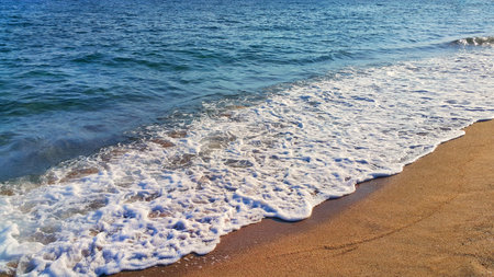 Sea wave with white foam on the coastal sand, natural close-up background