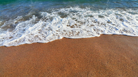Sea water with white foam in the coastal sand, natural close-up background