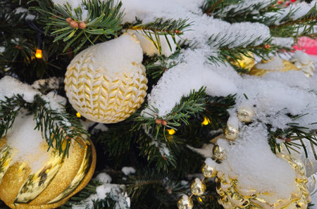 Branches of Christmas tree covered with snow with beautiful golden toys and garlands, close-upの写真素材