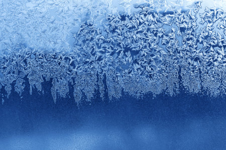Beautiful ice pattern on window glass, blue natural winter texture
