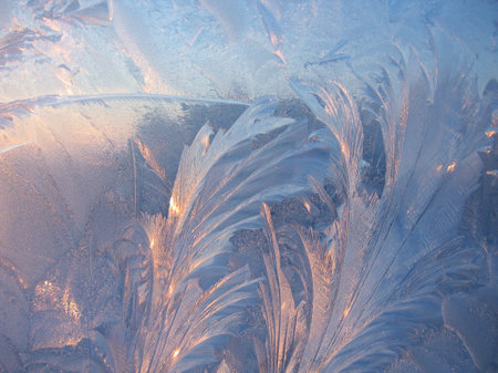 Beautiful ice pattern and sunlight closeup on window glass early in the morning, natural winter backgroundの写真素材