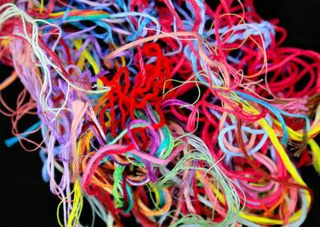 Close-up ball of multicolored tangled cotton threads for needlework on black background