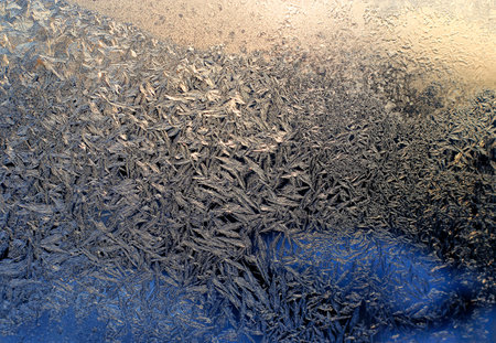 Beautiful ice pattern and sunlight close-up on winter window glassの写真素材