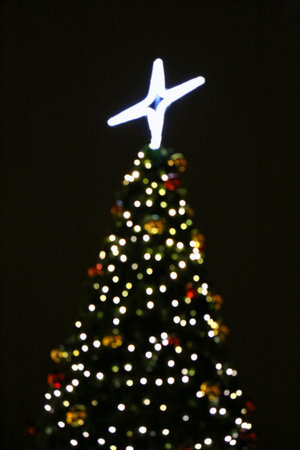Christmas tree, unfocused burning lights in the dark, holiday abstract background