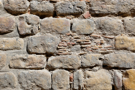Very old vintage wall from large stones of various shapes and bricks, close-up architectural backgroundの写真素材