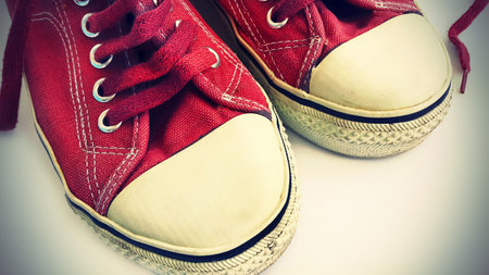 Old crimson sneakers, close-up on a white backgroundの写真素材