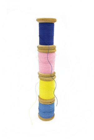 Spools of bright multi-colored threads stacked on top of each other, isolated on a white background