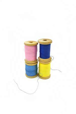 Spools of bright multi-colored threads stacked on top of each other, isolated on a white background