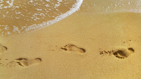 Nature background with sea water and footprints in the sand at the beachの写真素材