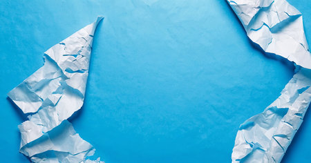 Crumpled scraps of white paper on a light blue background. Space for text.の写真素材