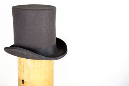 Elegant classic gray top hat with a flat crown and wide brim in the wooden hat block. Topper headpiece Isolated on white background. Copy space. Clipping pathの写真素材