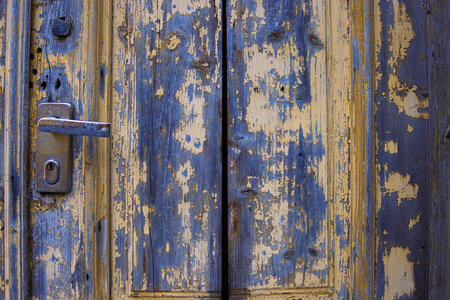 Vintage rustic door with a metallic lock and door handle. Detailed old wooden texture with chipped paint and a worn-out surface. Antique doorknob design. Backdrop for creative projects. Copy spaceの写真素材