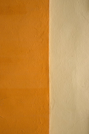 Vibrant orange wall texture with a subtle beige stripe, perfect for background, design inspiration or artistic project. Image of imperfections and unique details of an outdoor painted surface.の写真素材