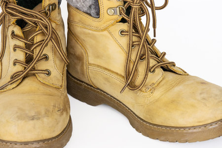 Vintage yellow leather hiking boots with laces in a worn-in look. Beige used military shoes with...