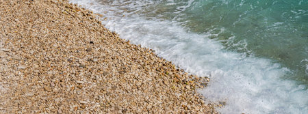 Beautiful pebbles beach with waves and blue sky. Relaxing aerial scene, summer vacation. Holiday template banner. Waves surf with amazing blue ocean lagoon, sea shore, coastline. Copy space.の写真素材