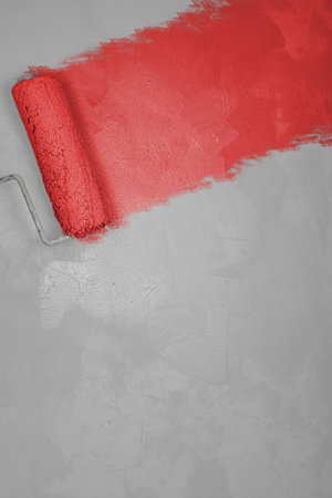 Painting wall with with roller brush into red white colors. Home renovation concept. Renovating apartment. Red textured background, place for text. Simple minimalist design. Close up. Empty copy spaceの写真素材