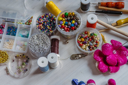 Handcraft artist workspace. Laptop, colorful beads, felt, tools, scissors, needles, thread spools, glue, containers, pliers, wire. Creative chaos concept. Flat lay.の写真素材