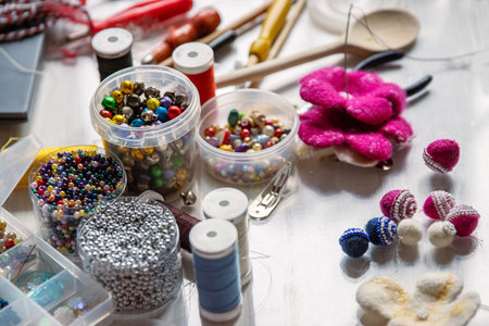 Creating Christmas ornaments. Handcraft artist workspace. Laptop, colorful beads, felt, tools, scissors, needles, thread spools, glue, containers, pliers, wire. Creative chaos concept. Flat lay.の写真素材