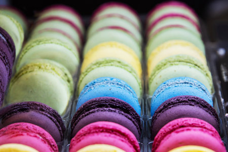 Various colorful macarons or French macaroons in a row on a coffee shop shelf, sweet meringue-based confection made with egg white, icing sugar, granulated sugar. Confectionery store. Selective focusの写真素材