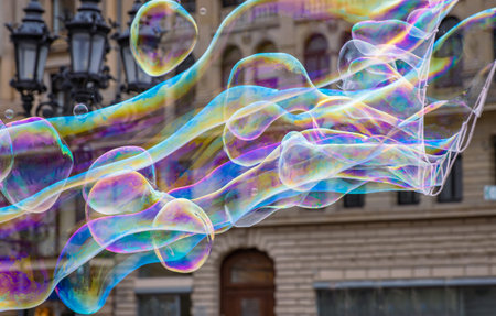 Many multicolored giant soap bubbles flying in the air on a windy day. Huge bubbles are stretching...