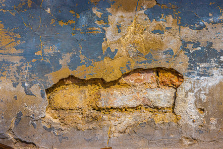 Old damaged broken shabby red brick wall of an old building. Brick texture with scratches and cracks. Grunge background with cracked gray blueish stucco. Close up. Copy spaceの写真素材