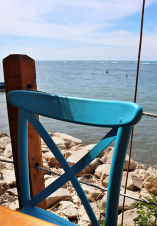 DÃ¼rres, Albania - September, 3rd, 2022: Spectacular view to the Adriatic sea from a restaurant. Beautiful wooden retro chair hand painted turquoise. Hot summer day.の写真素材