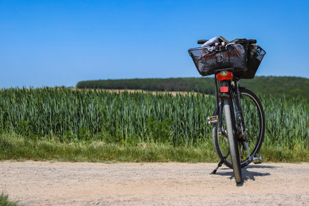 WÃ¼rzburg, Bavaria, Germany - May 27th 2023. Bicycle with the shopping basket standing on the country road in front of the wide rye field on a spring sunny day with the bright blue sky.の写真素材