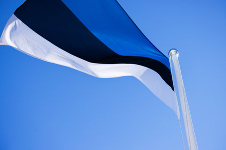 National Estonian flag waving against a clear blue sky, symbolizing national pride and identity with distinct horizontal blue, black, and white stripes. Copyspaceの写真素材