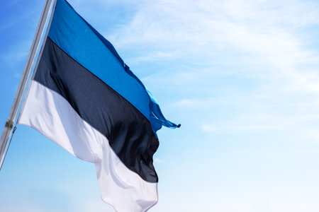 National Estonian flag waving against a partly cloudy sky, symbolizing national pride and identity with distinct horizontal blue, black, and white stripes. Copyspaceの写真素材