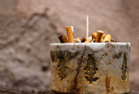Closeup of an ashtray filled with numerous cigarette butts, symbolizing smoking habits and litter, urban pollution, unhealthy lifestyle, littering. Side view. Copyspaceの写真素材