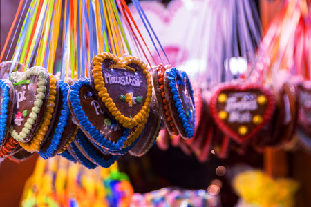 A colorful Christmas market in Berlin. Lady is selling heart shaped gingerbread with sweet messages, cotton candy, and vibrant sweets, highlighting the festive charm of German holiday traditionの写真素材