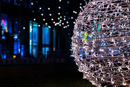 Intertwined white sliver string lights on the street next to Christmas market.. Crisscrossing glowing LED garland with small bright bulbs against dark background. Berlin, Germany. Copy spaceの写真素材