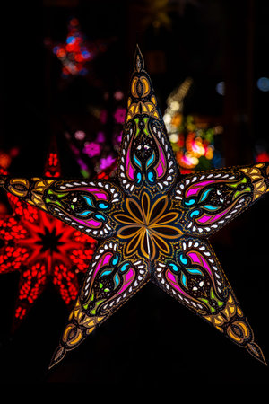 Handcrafted Christmas star lantern with intricate ornament, lighting up a bustling Christmas market with vibrant colors, creating a cozy holiday atmosphereの写真素材