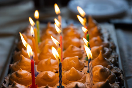 Closeup 15 colorful lit candles at the birthday party at home. Large homemade chocolate cake, decorated with meringues and whipped cream. Celebration concept. Selective focus.の写真素材