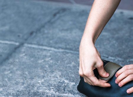 Closeup of young woman's hands opening a leather pouch, which is laying on a stone floor. Detailed...